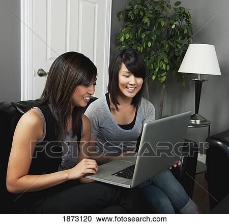 Stock Image - two young women working on a laptop computer. Fotosearch