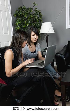 Stock Photo - two young women working on a laptop computer. Fotosearch