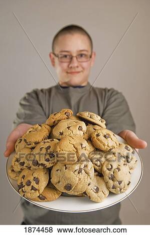 a boy holding a plate of chocolate chip cookies View Large Photo Image Stock Photo - a boy holding a plate of chocolate chip cookies. Fotosearch
