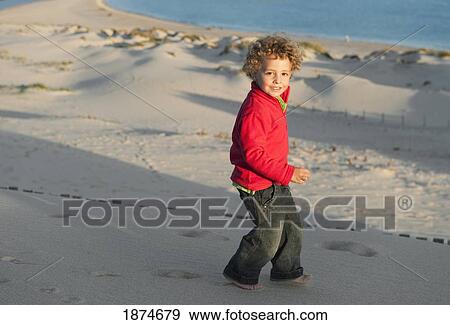 Stock Photo - a boy walking in the sand. Fotosearch