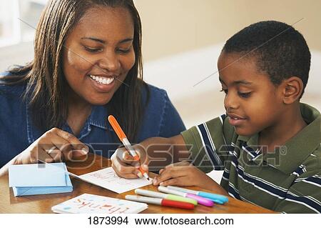 a boy writing thank you cards with his mother watching View Large Photo Image Picture - a boy writing thank you cards with his mother watching. Fotosearch