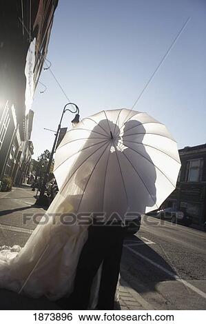 Stock Photograph - a bride and groom behind a white umbrella. Fotosearch