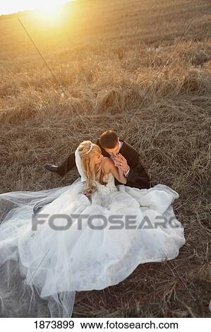 Stock Photo - a bride and groom sitting in a field. Fotosearch