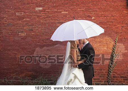 Stock Photography - a bride and groom under a white umbrella. Fotosearch