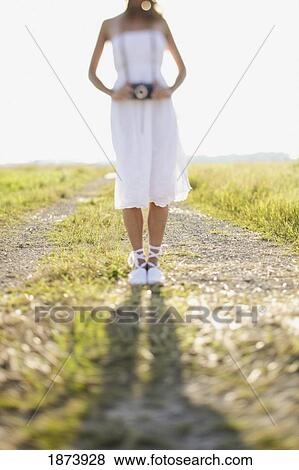 a bride standing on a dirt road in a field with a camera around her neck View Large Photo Image Stock Photo - a bride standing on a dirt road in a field with a camera around her neck. Fotosearch