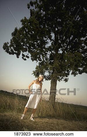 Stock Image - a bride standing under a tree in a field. Fotosearch