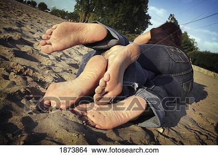 Picture - a couple laying together on the sand. Fotosearch