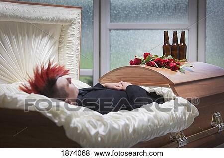 Stock Photo - a deceased young man laying in a coffin with beer bottles on top of it. Fotosearch