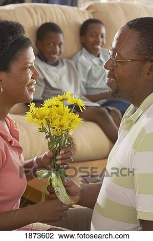 a father giving flowers to the mother while sons are watching View Large Photo Image Stock Image - a father giving flowers to the mother while sons are watching. Fotosearch
