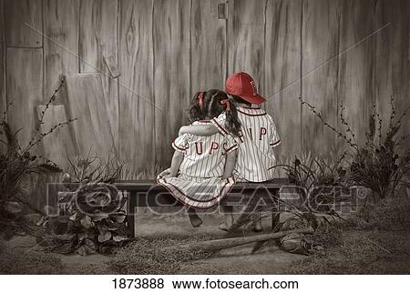 a girl and boy sitting on a bench wearing matching baseball uniforms View Large Photo Image Stock Photo - a girl and boy sitting on a bench wearing matching baseball uniforms. Fotosearch