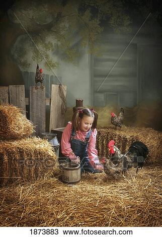 Stock Image - a girl feeding the birds in a barn. Fotosearch