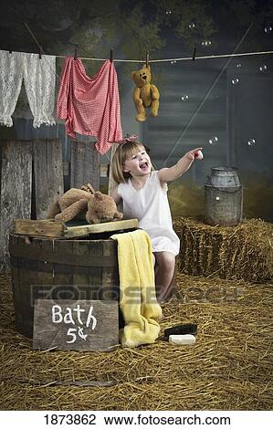 a girl pointing at bubbles and standing beside a barrel with a bath sign View Large Photo Image Stock Image - a girl pointing at bubbles and standing beside a barrel with a bath sign. Fotosearch