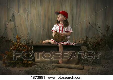 a girl sitting on a bench wearing a vintage girl's baseball uniform View Large Photo Image Stock Image - a girl sitting on a bench wearing a vintage girl's baseball uniform. Fotosearch