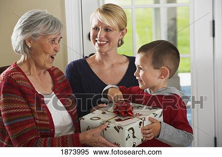 a grandson giving a gift to his grandmother while the mother watches View Large Photo Image Stock Photography - a grandson giving a gift to his grandmother while the mother watches. Fotosearch