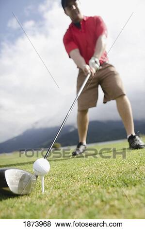 Stock Photo - a man ready to hit a golf ball on a tee. Fotosearch