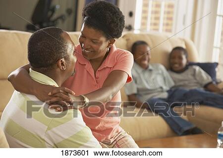 Stock Image - a mother and father being affectionate while sons are watching. Fotosearch