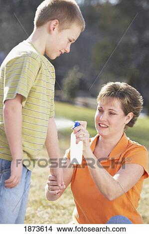 a mother spraying insect repellent on her son View Large Photo Image Picture - a mother spraying insect repellent on her son. Fotosearch