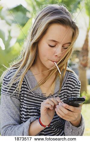 a preteen girl eating a sucker and using her cellphone View Large Photo Image Stock Photo - a preteen girl eating a sucker and using her cellphone. Fotosearch