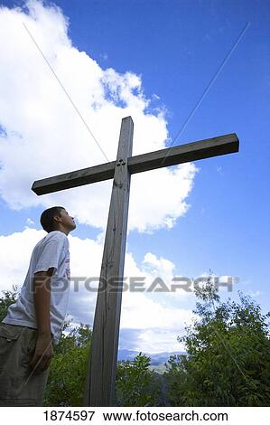 Stock Photo - a teenage boy looking up to the cross. Fotosearch