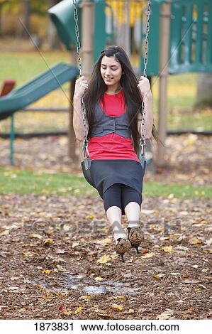 a teenage girl sitting on a swing in a playground View Large Photo Image Stock Image - a teenage girl sitting on a swing in a playground. Fotosearch