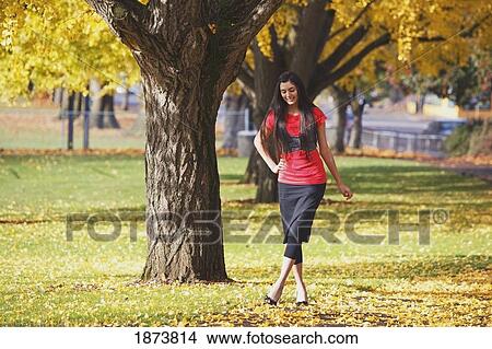 Picture - a teenage girl walking through a park in autumn. Fotosearch