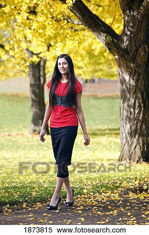 Stock Photography - a teenage girl walking through a park in autumn. Fotosearch