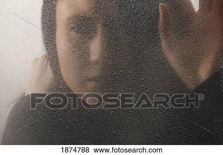 Stock Photo - a woman behind a cold, frosted window. Fotosearch