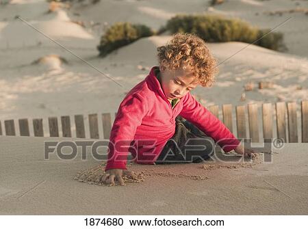 Stock Image - a young boy playing on a sand dune. Fotosearch