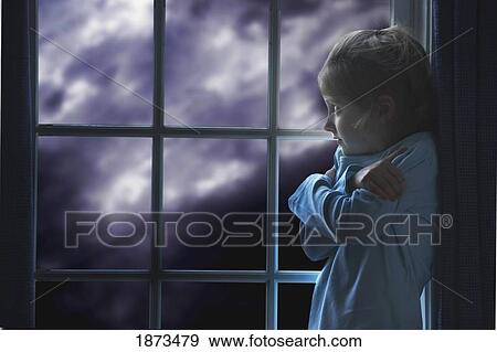 Stock Photo - a young girl feeling fear as she watches a storm out the window. Fotosearch
