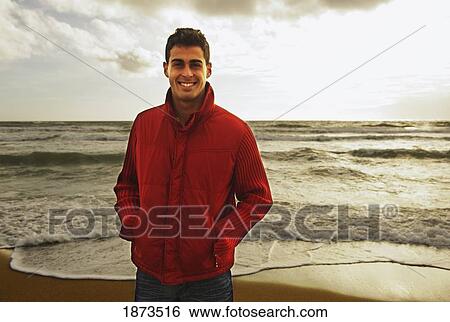 a young man standing on a beach View Large Photo Image Stock Photograph - a young man standing on a beach. Fotosearch