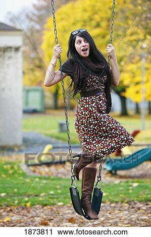 a young woman standing on a swing at a playground in autumn View Large Photo Image Stock Image - a young woman standing on a swing at a playground in autumn. Fotosearch