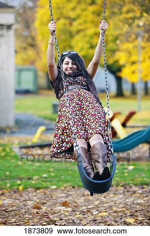 a young woman standing on a swing at a playground in autumn View Large Photo Image Stock Photo - a young woman standing on a swing at a playground in autumn. Fotosearch