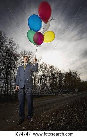 alberta, canada; a businessman standing on the side of the road holding balloons View Large Photo Image Stock Photo - alberta, canada; a businessman standing on the side of the road holding balloons. Fotosearch