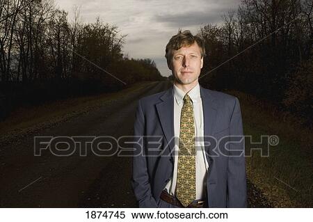 Stock Photography - alberta, canada; a businessman standing on a road. Fotosearch