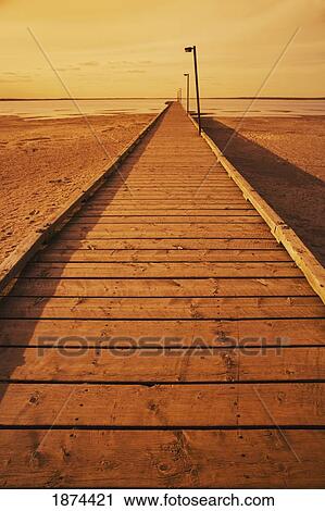 Stock Image - alberta, canada; a pier on the sand leading out to the lake. Fotosearch