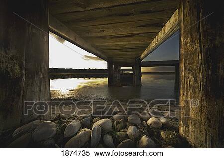 Stock Photography - alberta, canada; underneath a pier going out into the lake. Fotosearch