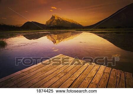 Stock Photography - banff, alberta, canada; a dock on a mountain lake during a sunset. Fotosearch