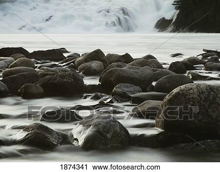 Stock Image - banff, alberta, canada; rocks in a mountain river with a cascade. Fotosearch