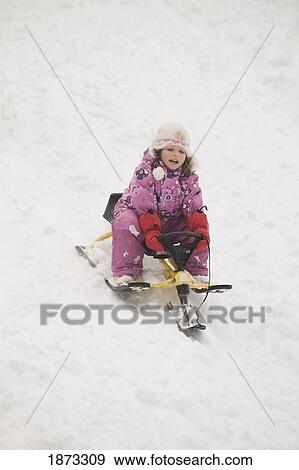 Stock Photo - blairmore, alberta, canada; young girl sledding down a hill. Fotosearch