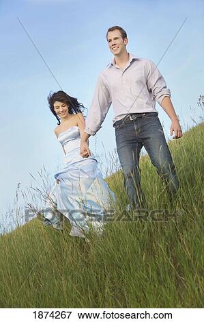 edmonton, alberta, canada; a couple running through the grass View Large Photo Image Stock Photo - edmonton, alberta, canada; a couple running through the grass. Fotosearch