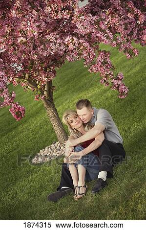 edmonton, alberta, canada; a couple sitting together on the grass under a tree View Large Photo Image Stock Photography - edmonton, alberta, canada; a couple sitting together on the grass under a tree. Fotosearch