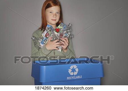 Stock Image - edmonton, alberta, canada; a girl putting plastic bottles and juice boxes into a blue recycle box. Fotosearch