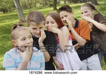 Stock Photograph - edmonton, alberta, canada; a group of children standing in a row and telling secrets to each other. Fotosearch