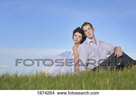 edmonton, alberta, canada; a man and woman sitting on the grass View Large Photo Image Picture - edmonton, alberta, canada; a man and woman sitting on the grass. Fotosearch