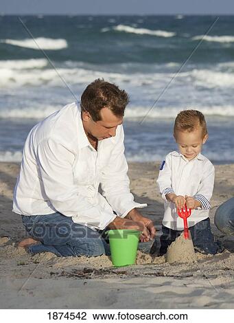 Stock Image - Father and child playing on beach. Fotosearch
