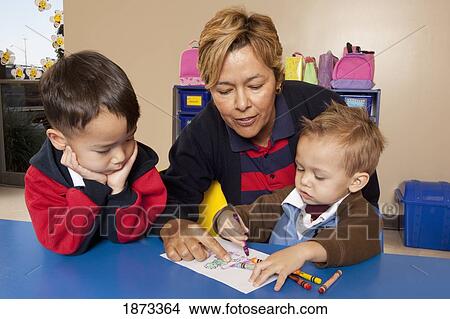 fort lauderdale, florida, united states of america; a teacher with two young boys coloring at a table in a classroom View Large Photo Image Picture - fort lauderdale, florida, united states of america; a teacher with two young boys coloring at a table in a classroom. Fotosearch