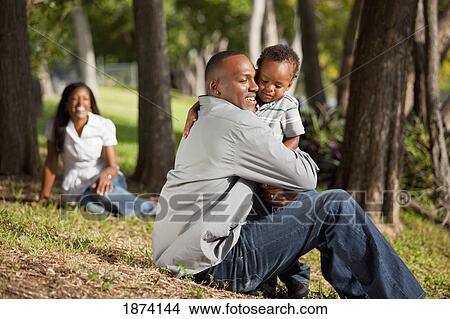 Picture - fort lauderdale, florida, united states of america; a father hugs his young son while the mother watches. Fotosearch