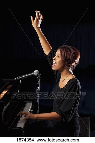 fort lauderdale, florida, united states of america; a woman playing the piano and singing in worship with her hand raised View Large Photo Image Picture - fort lauderdale, florida, united states of america; a woman playing the piano and singing in worship with her hand raised. Fotosearch