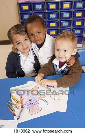 Stock Image - fort lauderdale, florida, united states of america; three young boys coloring at a table in a classroom. Fotosearch