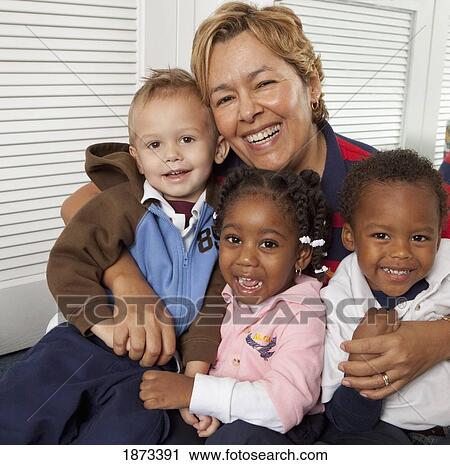 Stock Image - fort lauderdale, florida, united states of america; a teacher hugging three young children. Fotosearch